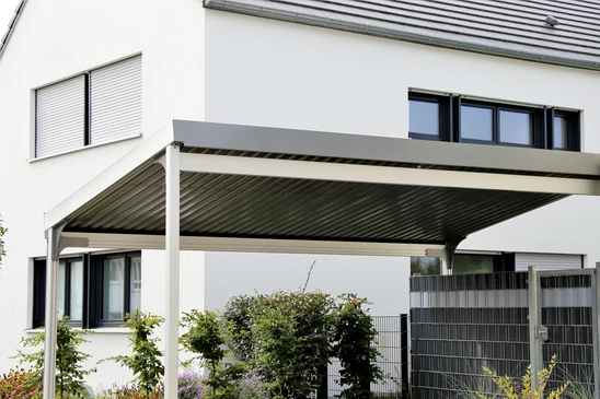 Extérieur résidentiel moderne avec pergola bioclimatique à lames orientables installée devant une maison contemporaine blanche