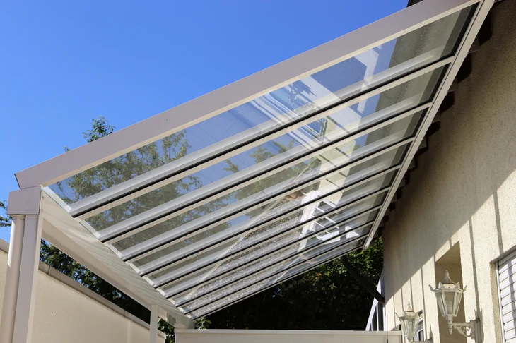 Scène extérieure montrant une pergola bioclimatique moderne adossée à une habitation