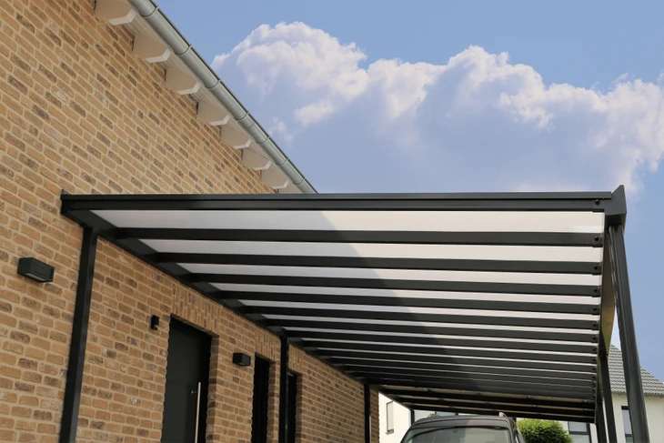 Pergola moderne en aluminium anthracite fixée sur façade en briques claires d'une maison contemporaine