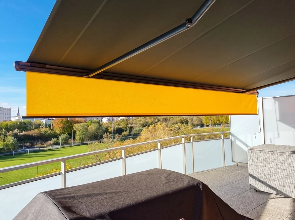 Store banne motorisée déployée sur une terrasse en hauteur avec vue urbaine et espaces verts
