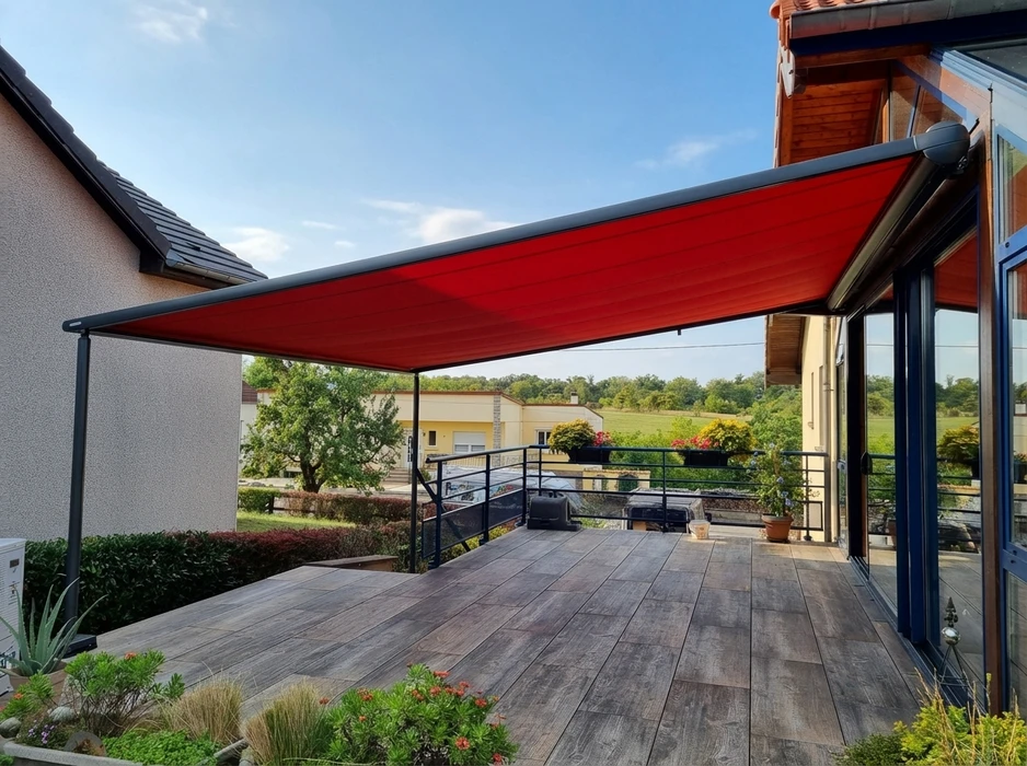 Terrasse extérieure avec store banne pergola à structure aluminium anthracite et toile rouge tendue sur poteaux frontaux