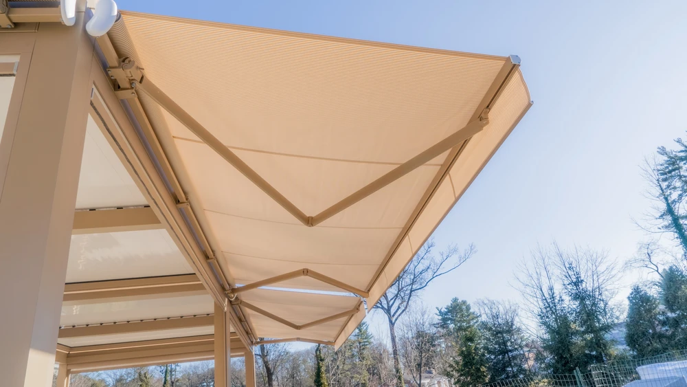 Terrasse extérieure d'une maison moderne avec store banne beige déployé créant une zone d'ombre