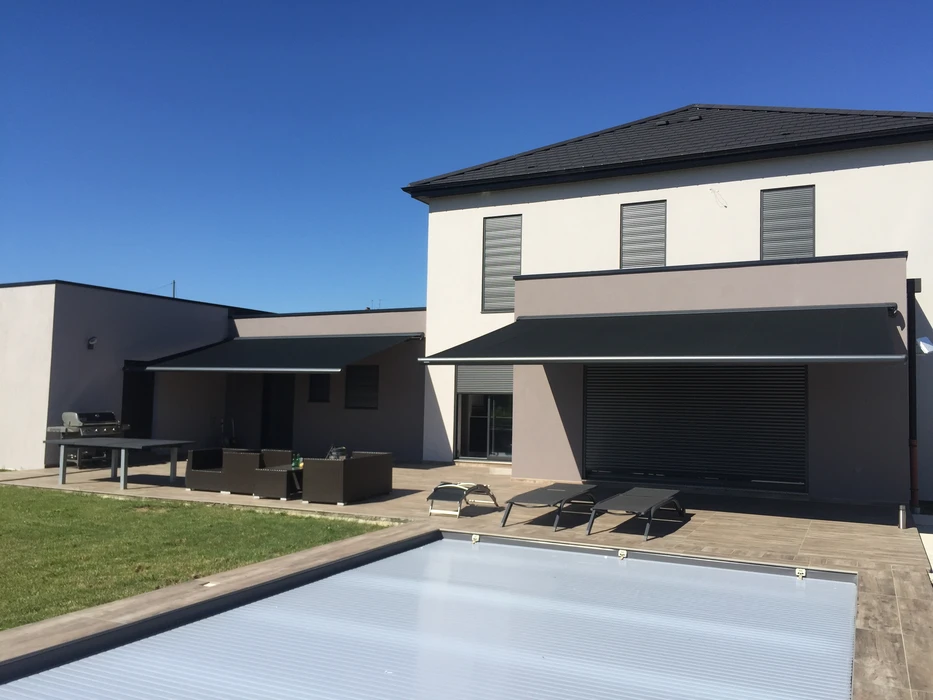 Terrasse extérieure d'une villa contemporaine avec store banne motorisé déployé, toile grise imperméable sur structure aluminium anthracite