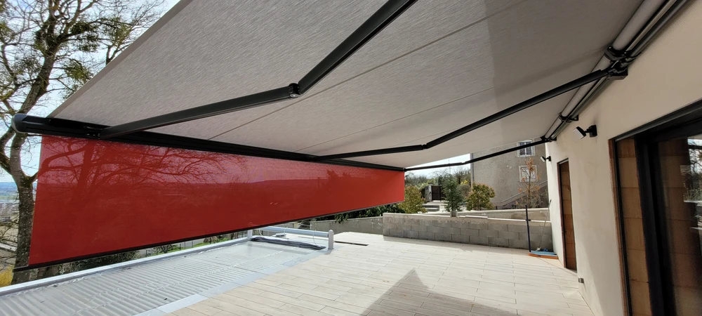 Terrasse extérieure d'une villa contemporaine avec store banne motorisé déployé, toile grise imperméable sur structure aluminium anthracite