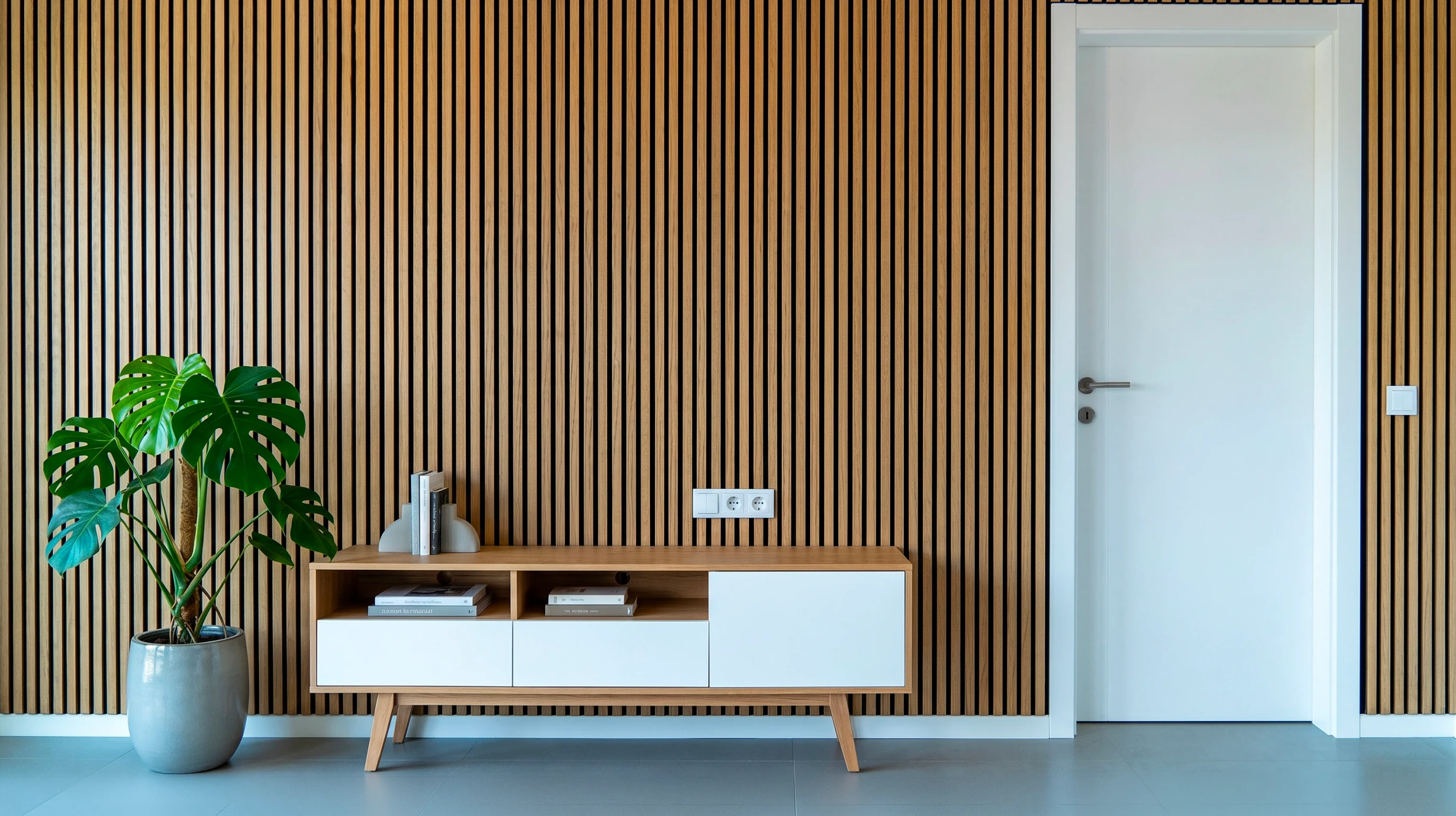 Trois panneaux décoratifs muraux présentant des motifs abstraits dorés sur fond blanc, disposés côte à côte dans un espace intérieur moderne aux murs gris clair