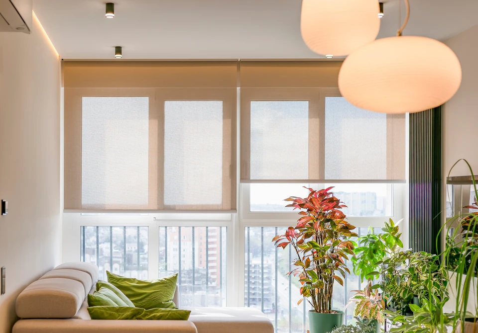 Salon moderne avec canapés gris modulaires disposés face à une grande baie vitrée coulissante donnant sur terrasse et jardin arboré